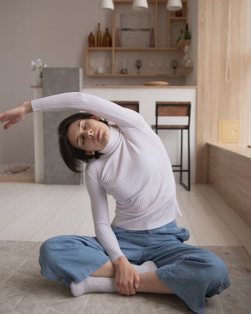 Étirement latéral en position assise, dans la lumière d'une pièce claire